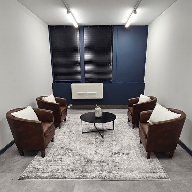 Professional office interior design for a medical waiting area, featuring leather tub chairs, a charcoal rug, and architectural navy wall accents by edge.ids.