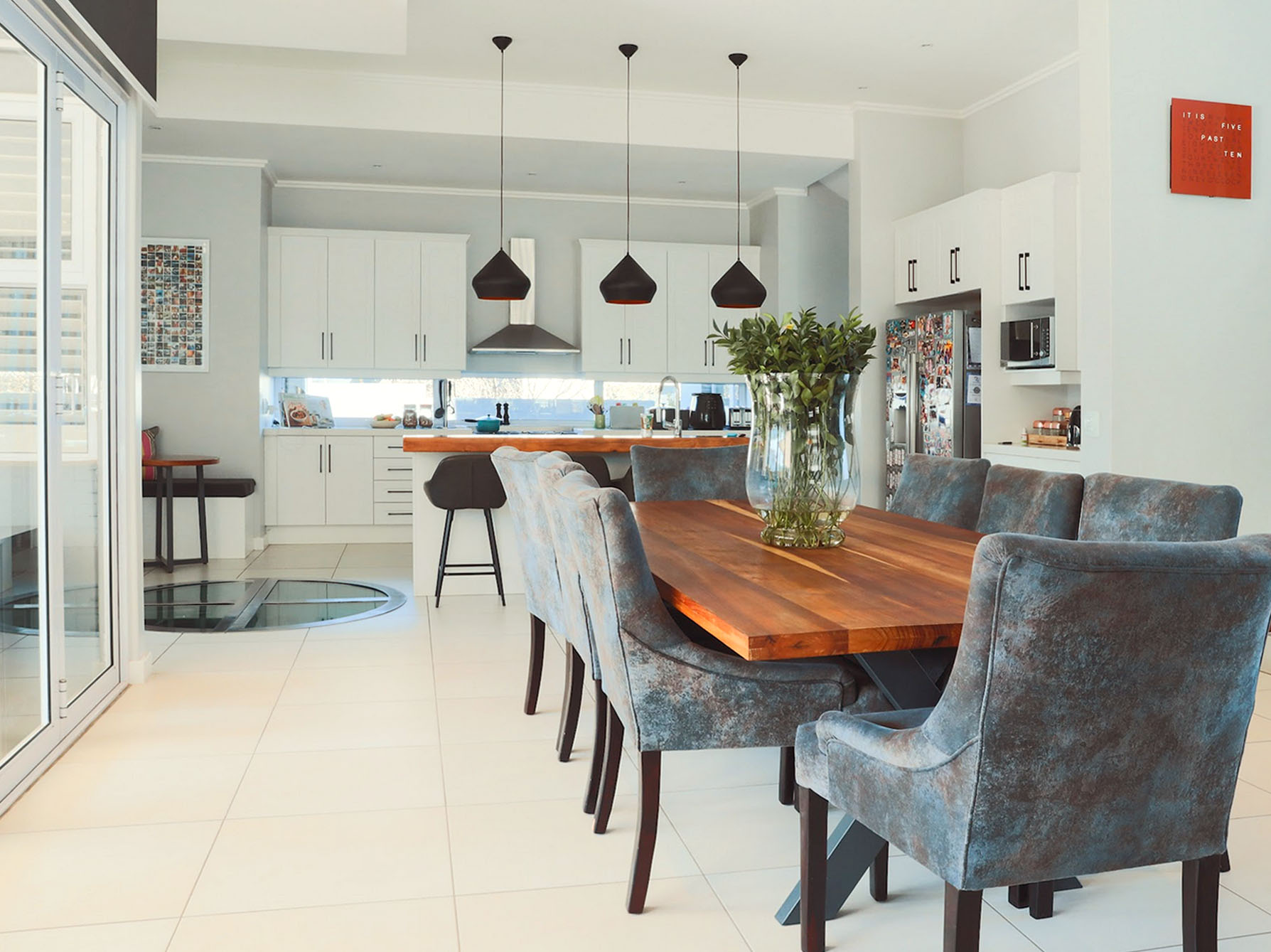 Open-plan dining and kitchen area featuring a natural wood dining table and textured seating at Waterfall Country Estate.