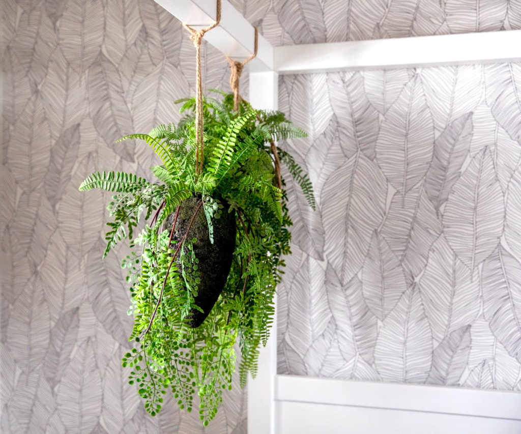Close-up of monochromatic leaf-patterned wallpaper and a hanging green fern in the guest bedroom at Serengeti Estate.