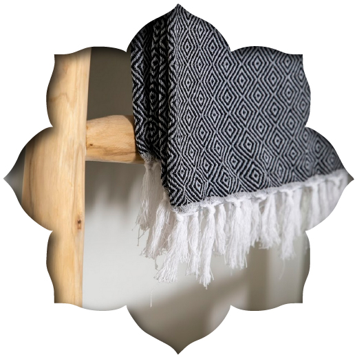 Close-up of a black and white geometric throw and natural wood ladder, showcasing monochromatic textures in a Serengeti Estate apartment.
