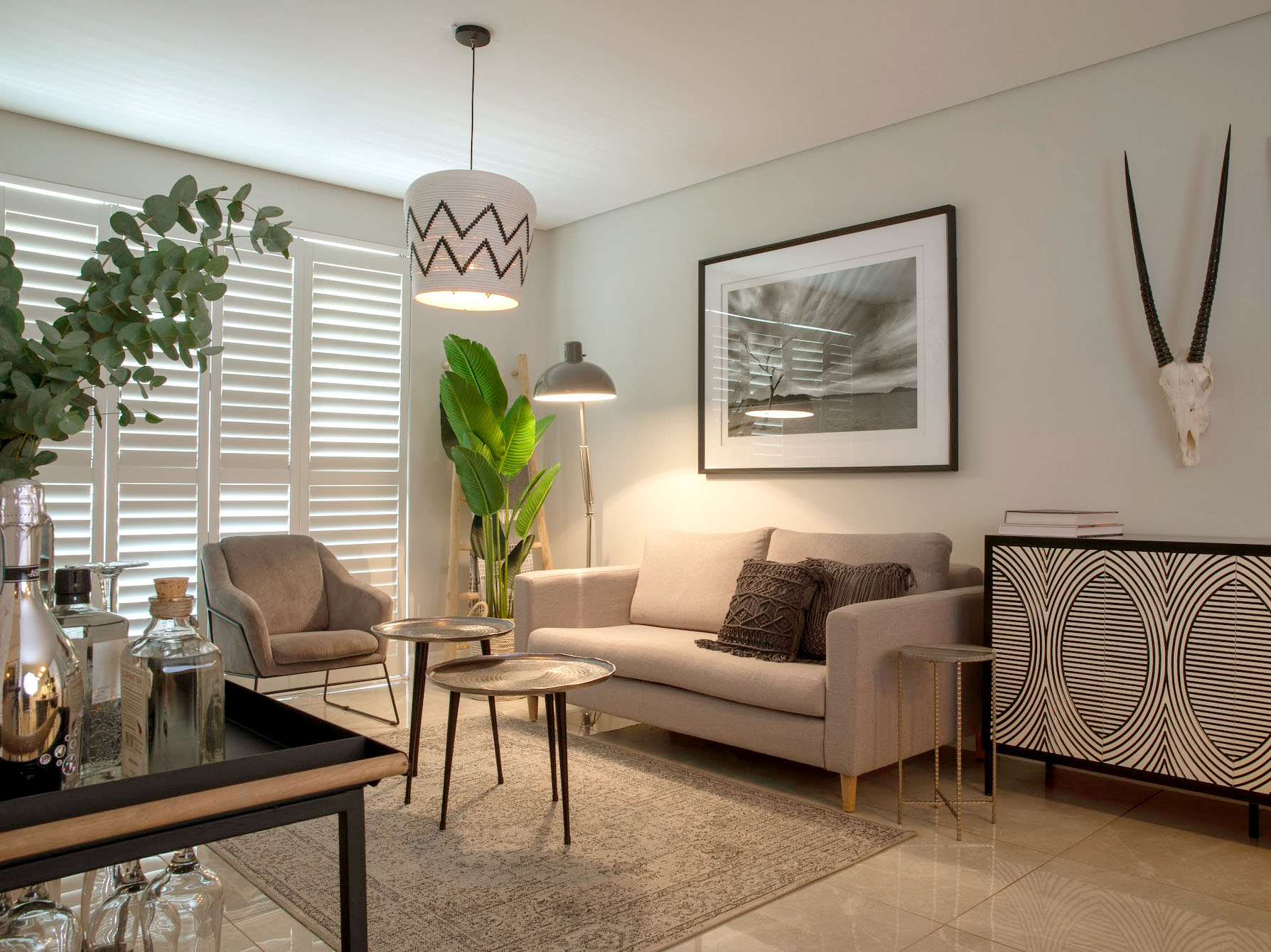 Modern monochromatic living room at Serengeti Estate featuring a custom black and white geometric server, natural bush-inspired decor, and grey furnishings.